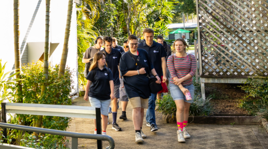 A group of STEPS Pathways College students walking together along a campus pathway lined with greenery and buildings.