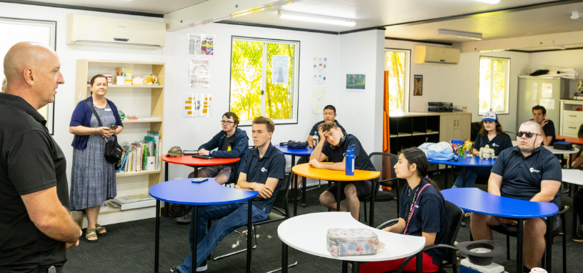 STEPS Pathways College students seated at tables in a classroom while a facilitator speaks at the front of the room.