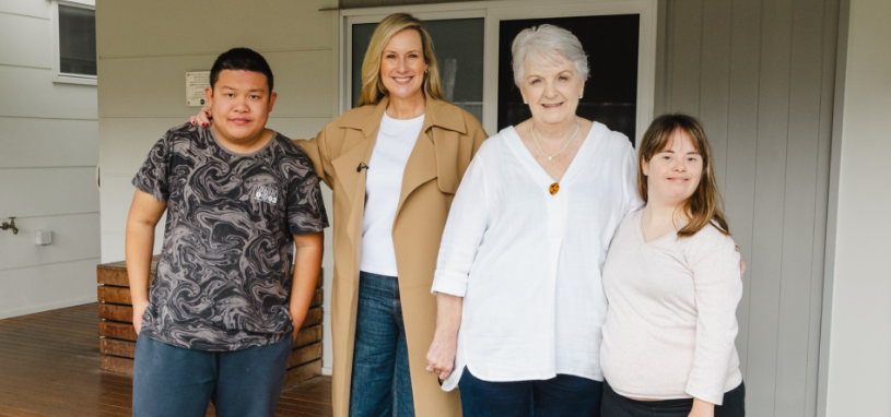Melissa Doyle and Carmel Crouch standing together in the centre, with STEPS Pathways College participants on either side, posed outside a campus building.