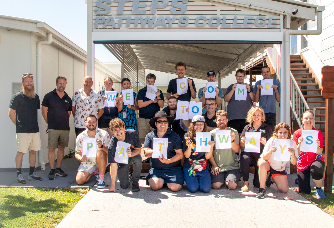 STEPS Pathways College participants and staff outside holding up letters that spell out 'Welcome to Pathways'.