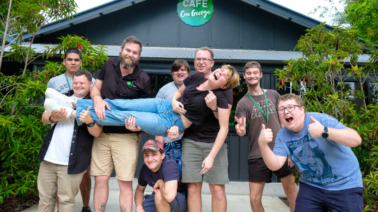 A group of STEPS students standing together outside STEPS Café on George, with the café building and entrance visible behind them.