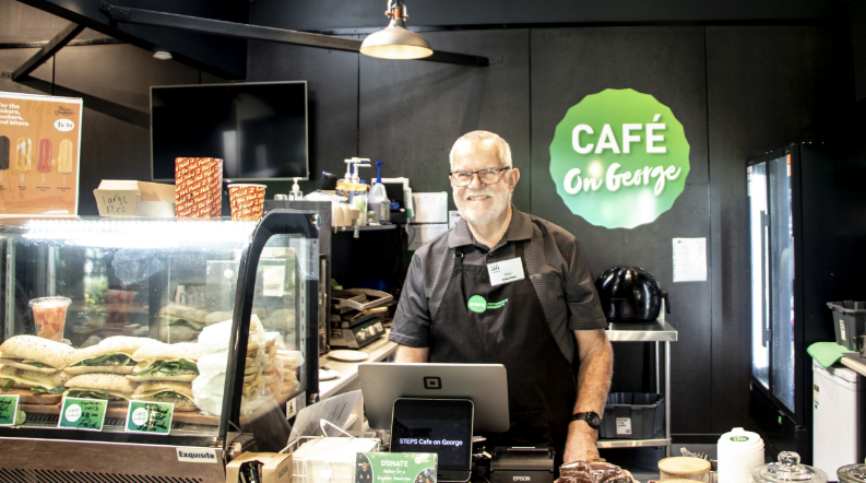 A volunteer smiling while working the cash register at the STEPS Café on George.