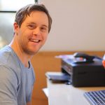 Young-man-sitting-at-desk-smiling