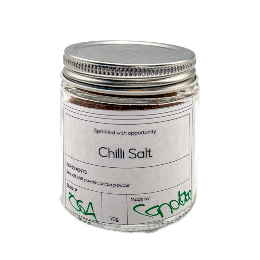 Glass jar of chilli salt with a silver lid and product label, showcasing a seasoning created through the Pathways to Plate program.