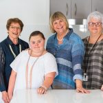 four women standing in a kitchen