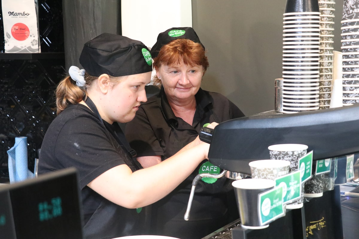 STEPS Pathways College student being taught how to use the coffee machine at Café on George