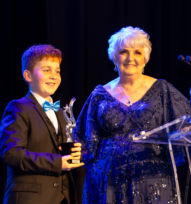 STEPS Pathways College Young Ambassador, Nate Nelson, standing onstage next to STEPS Managing Director, Carmel Crouch after receiving an award for their ongoing commitment and support.