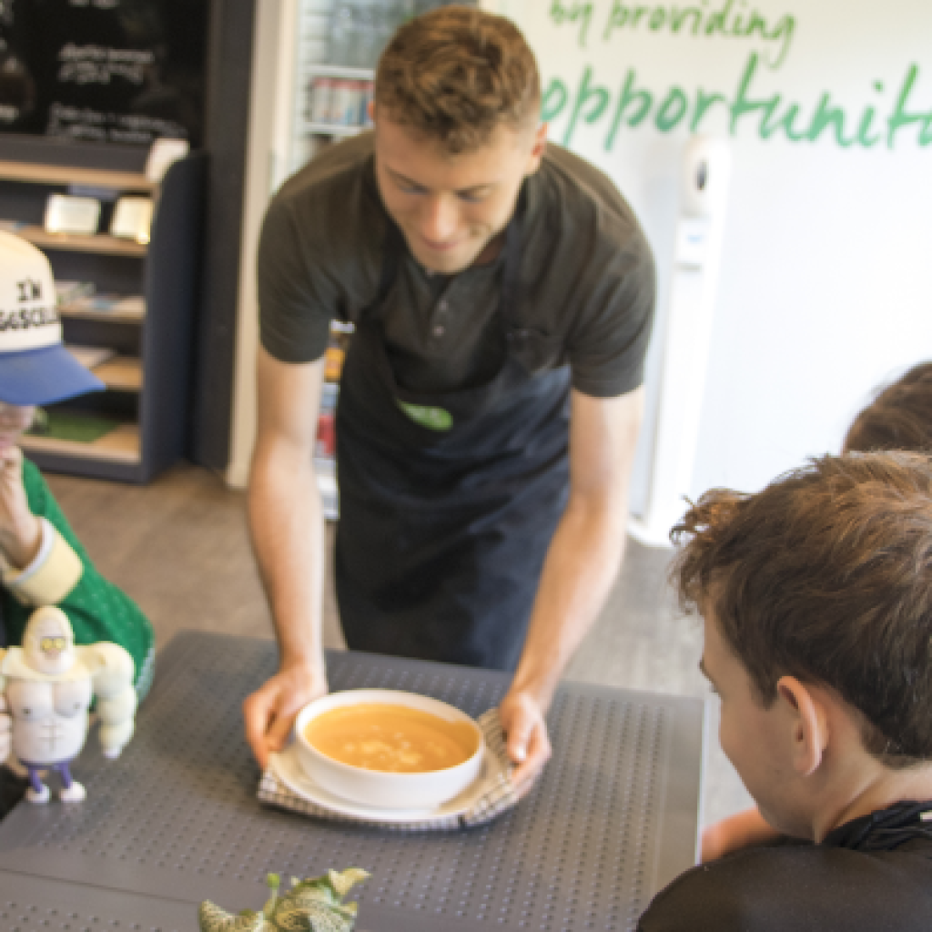 STEPS Café on Georges staff placing a bowl of fresh tomato soup on a table