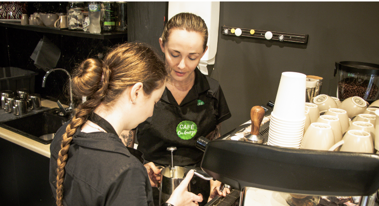 STEPS Café on George staff working with a STEPS Pathways College student to make a fresh coffee.