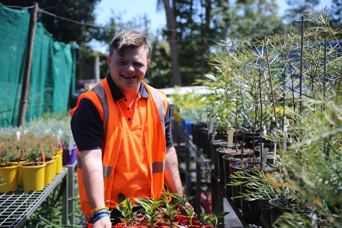 Male standing holding a tray of plants at the STEPS Nursery