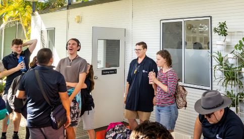 A group of STEPS Pathways College participants gather outside a classroom building, chatting and socialising during a break between activities.