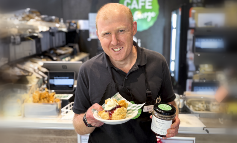 STEPS Café on George staff holding a plate with scons and a jar of Pathway's to Plate's Strawberry Jam