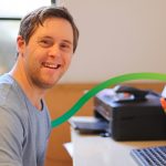 Young man with down syndrome sitting in front of desktop computer